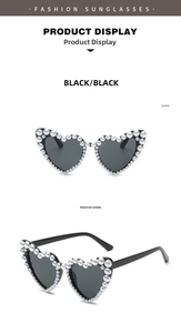 Detailed view of heart shaped sunglasses with black frames and white faux pearl accents