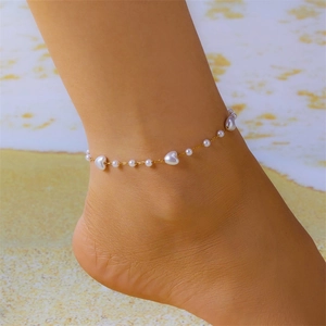 Golden chain anklet with white heart pearls worn on a beach background, summer style