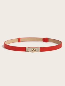 Detail of red skinny belt with sparkling rhinestone lock buckle on cream background