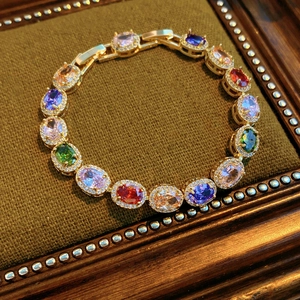 Detailed macro of vintage gold bracelet with multi-color oval gemstones on green velvet