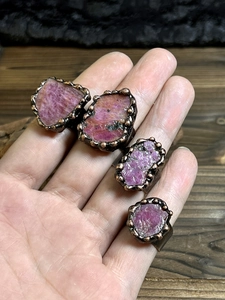 Macro detail of natural pink raw stones and textured bronze metal rings for women