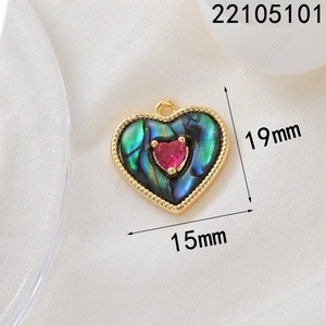 Macro shot of 18K gold plated heart pendant with abalone shell and pink zircon inlay