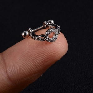 Macro shot of silver zircon cartilage earring with circular screw ball on fingertip
