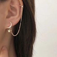 Detail view of gold moon and star earring set with zircon stones and chain link
