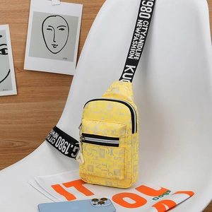 Detail of yellow canvas chest bag with grey letter print and wide black branded shoulder strap