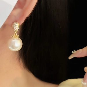Orecchini a goccia in perla placcati oro con zirconi, indossati da una modella
