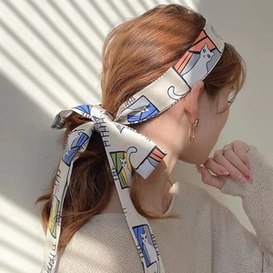 Long silk scarf headband with artistic cartoon cat print shown on model with hair bow