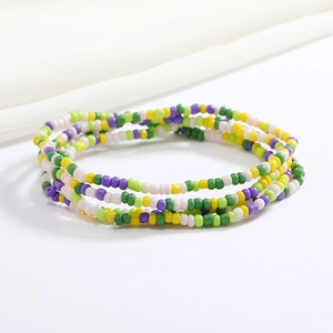 Close-up of colorful beaded body chains in green, yellow, purple, and white glass beads
