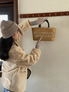 Detalle de atuendo invernal con chaqueta polar beige, gorro de punto y bolso de paja