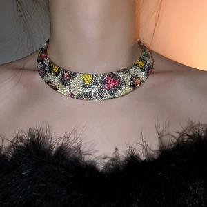 Close-up of golden collar necklace with multicolor leopard pattern rhinestones on model