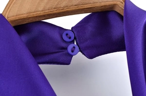 Detail eines lila Satin-Halterneck-Tops mit Zweiknopfverschluss und glatter Seidentextur