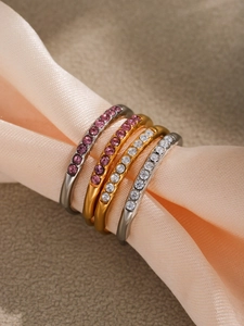 Close-up of 5A zircon rings on pink silk, showing gold and silver bands with purple stones
