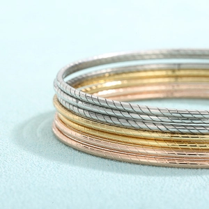 Dettaglio macro di bracciali a strati con texture a spirale in oro, argento e rosa