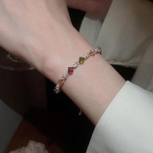 Close-up of multicolor zircon stones on a rose gold chain worn by a female model