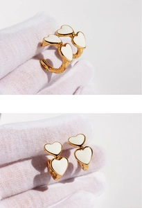 Detail of vintage white enamel heart earrings on a gold-tone metal base being held