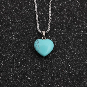 Detailed view of heart-shaped turquoise pendant with silver twist chain on dark background