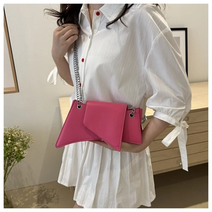 Close-up of magenta geometric leather crossbody bag with silver chain strap on model