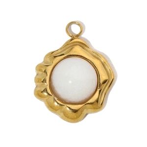 Detail view of a vintage white gemstone pendant with a wavy gold stainless steel base