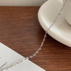 Minimalist S925 sterling silver heart-shaped link bracelet on a white porcelain plate