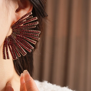 Detailed shot of a fan-shaped earring featuring deep red rhinestones and gold-tone metal