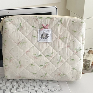 Detailed macro of floral quilted fabric pouch with embroidered elephant patch and pink bow