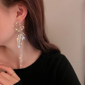 Elegant silver tassel earrings with sparkling rhinestones and bow design on female model