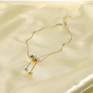 Detail of 18k gold and silver layered necklace with spherical bead charms on silk