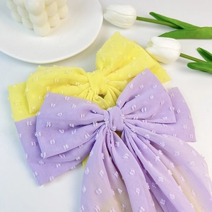 Close-up of elegant Swiss dot chiffon bow hair clips with long tassels in soft pastel colors