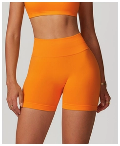 Detail of high-waist seamless bright orange yoga shorts with wide ribbed waistband
