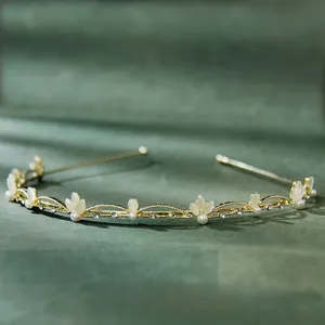 Close-up of golden leaf headband with cat-eye stones and pearls on dark green velvet