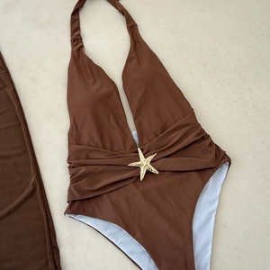 Detail of dark brown halter swimsuit with gold starfish ornament and pleated waist design