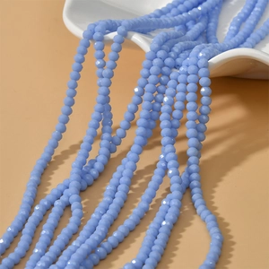 Macro detail of blue faceted 4mm rondelle glass beads on a peach background