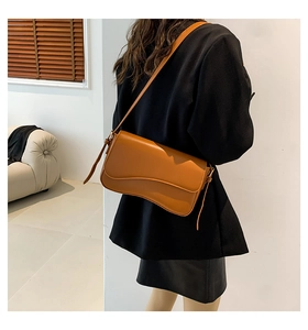 Brown leather shoulder bag with elegant wavy flap design shown on a model side view