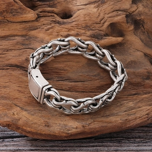 Close-up of vintage oxidized stainless steel chain link bracelet on a textured wood base
