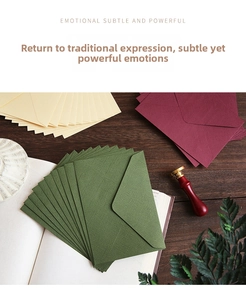 Detail of vintage linen-textured envelopes in burgundy, green, and cream on a wooden desk