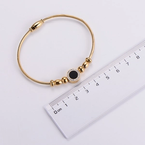 Detail of 18k gold plated wire bracelet with black enamel and crystals showing 6cm diameter