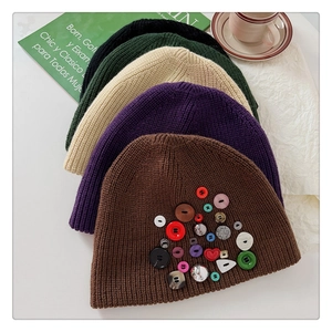 Detailed close-up of knitted beanies with colorful button accents in five stylish colors