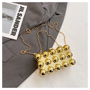 Macro detail of the golden 3D spheres and hard shell structure on an acrylic box clutch