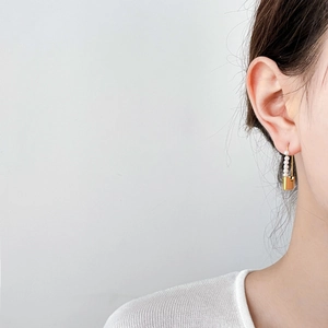 Detail of golden lock earring with white pearls worn by a model on a clean background