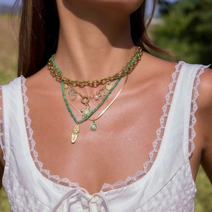 Detail view of layered 18K gold stainless steel chain necklace with green beads and charms