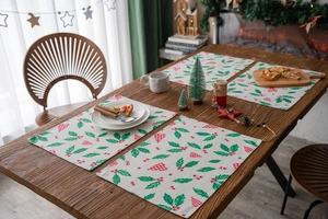 Close-up of Christmas placemats with holly leaf and red heart patterns on wooden table
