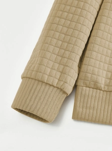 Detailed close-up of quilted waffle texture and ribbed cuffs on khaki outdoor sweatshirt