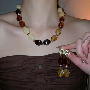 Vintage acrylic jewelry set featuring amber resin beaded necklace and drop earrings on a model