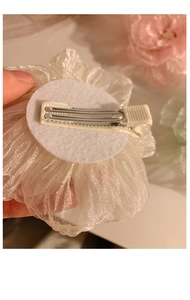 Detailed close-up of white mesh flower hair clip with a sturdy metal duckbill base