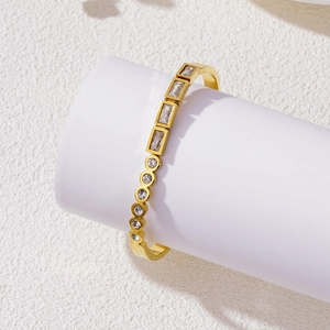 Elegant gold titanium steel bangle with geometric zircon crystals on a white pedestal