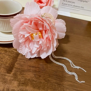 Close-up of pink fabric flower hair claw with rhinestone tassels and petal details