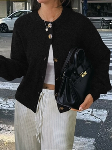 Gros plan détaillé d'un cardigan noir en maille avec boutons dorés et sac en cuir chic
