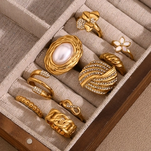 Set of gold stainless steel rings with floral, pearl, and chain motifs in a wood box
