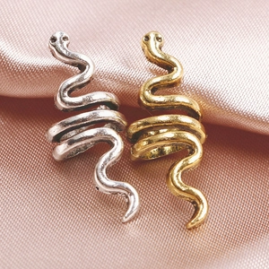 Macro shot of gold and silver spiral snake hair accessories on pink silk fabric