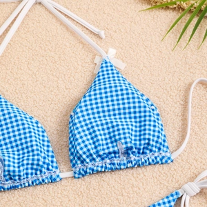 Detailed view of blue and white checkered bikini top with delicate white bows and ties